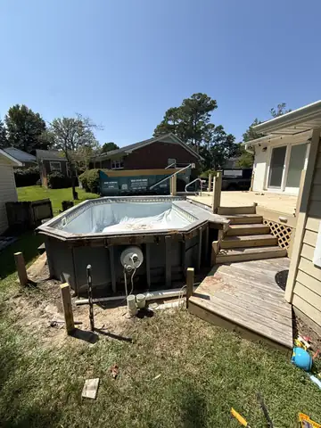 Above-ground pool and wood deck in a backyard before removal