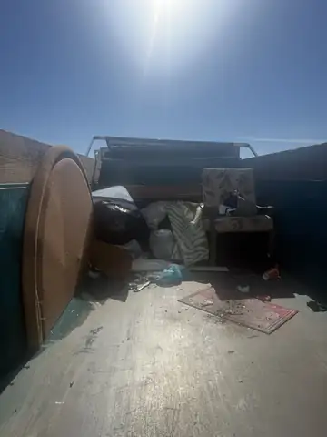 Dump trailer loaded with furniture, a round table and bags from a cleanout