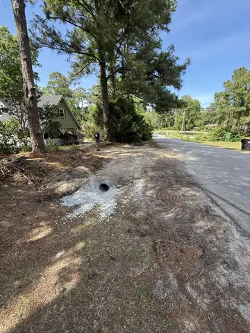 Culvert pipe end set in gravel along a road ditch