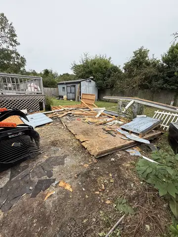 Torn-out deck boards and debris in a backyard, ready to haul off