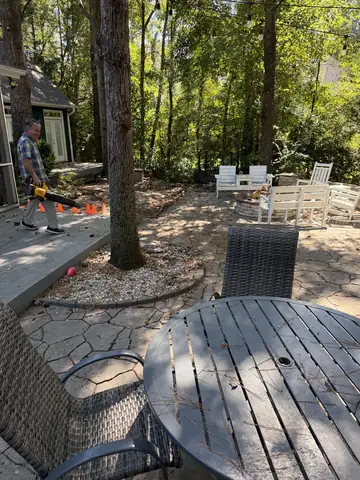 Patio being blown clean with a leaf blower after a backyard cleanup