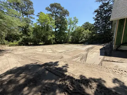 Lot graded for site prep next to a house under construction