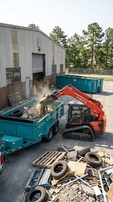 Kubota track loader loading tires, pallets and scrap into the dump trailer outside a warehouse