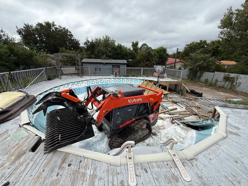 Kubota track loader with grapple tearing out an above-ground pool and deck in Wilmington, NC