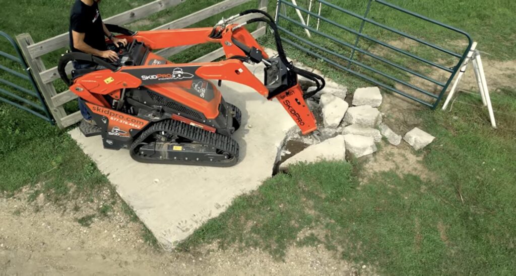 Skid steer with a hydraulic breaker breaking up concrete