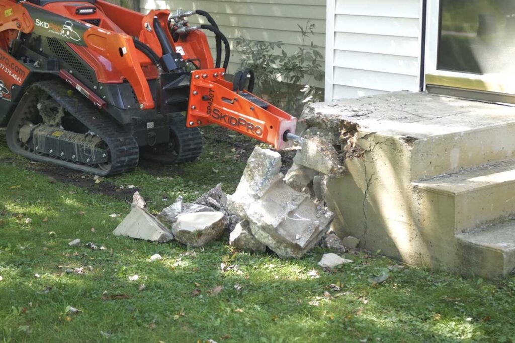 Skid steer breaking and loading old concrete